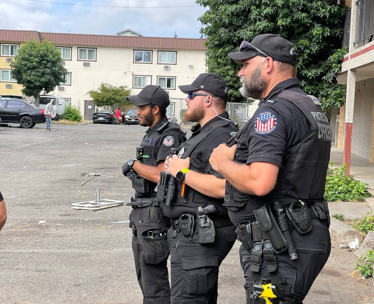 Three uniformed Falcon team members outside an apartment property