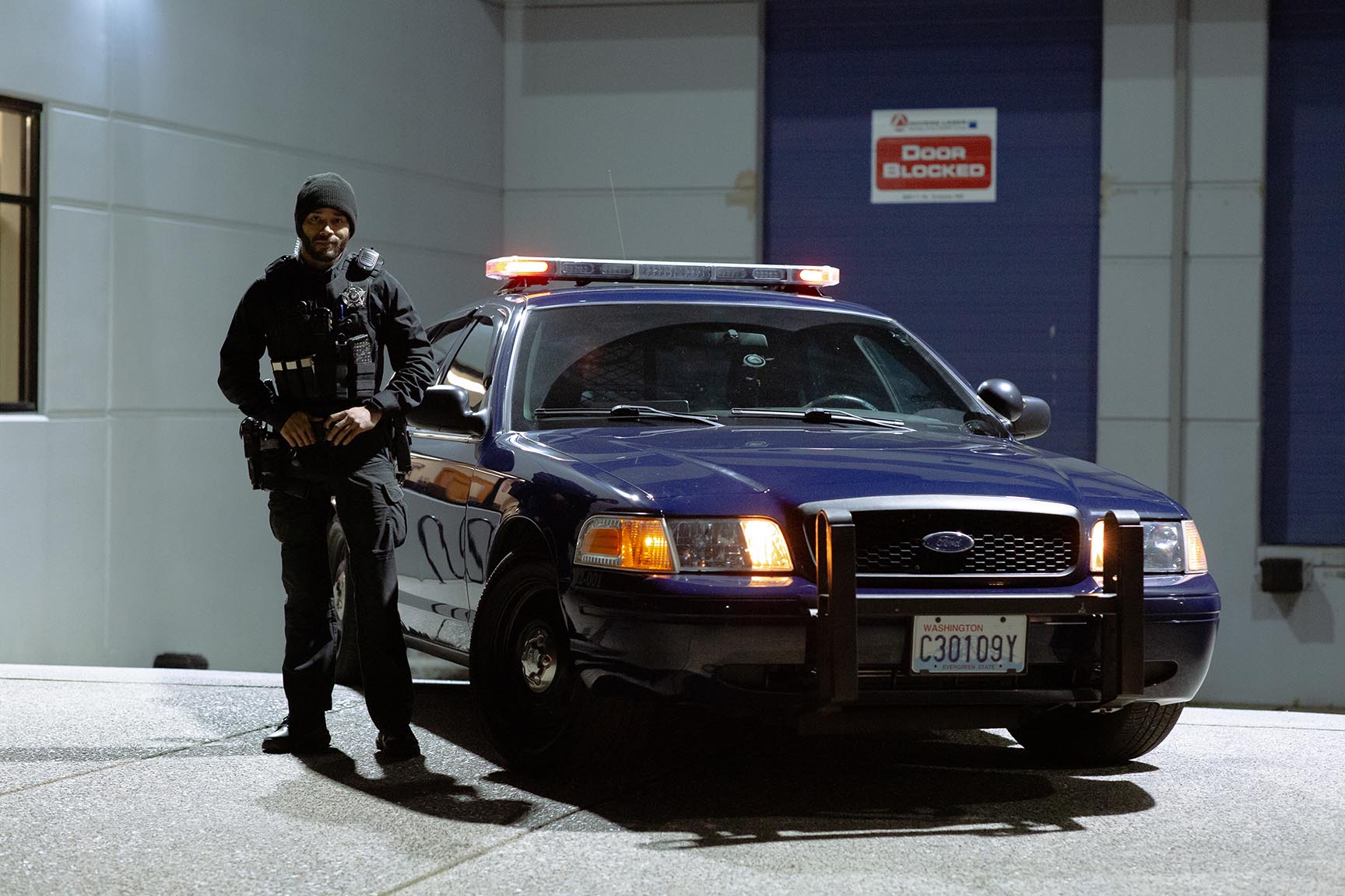 Uniformed Falcon team member beside a patrol sedan